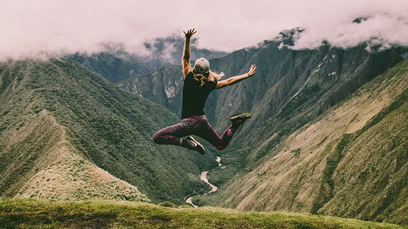 Junge Frau springt vor Freude in der Natur